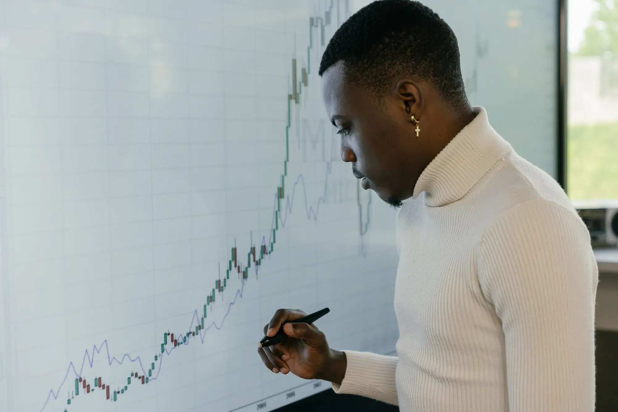 Jeune professionnel analysant une courbe de performance ascendante sur un grand tableau blanc